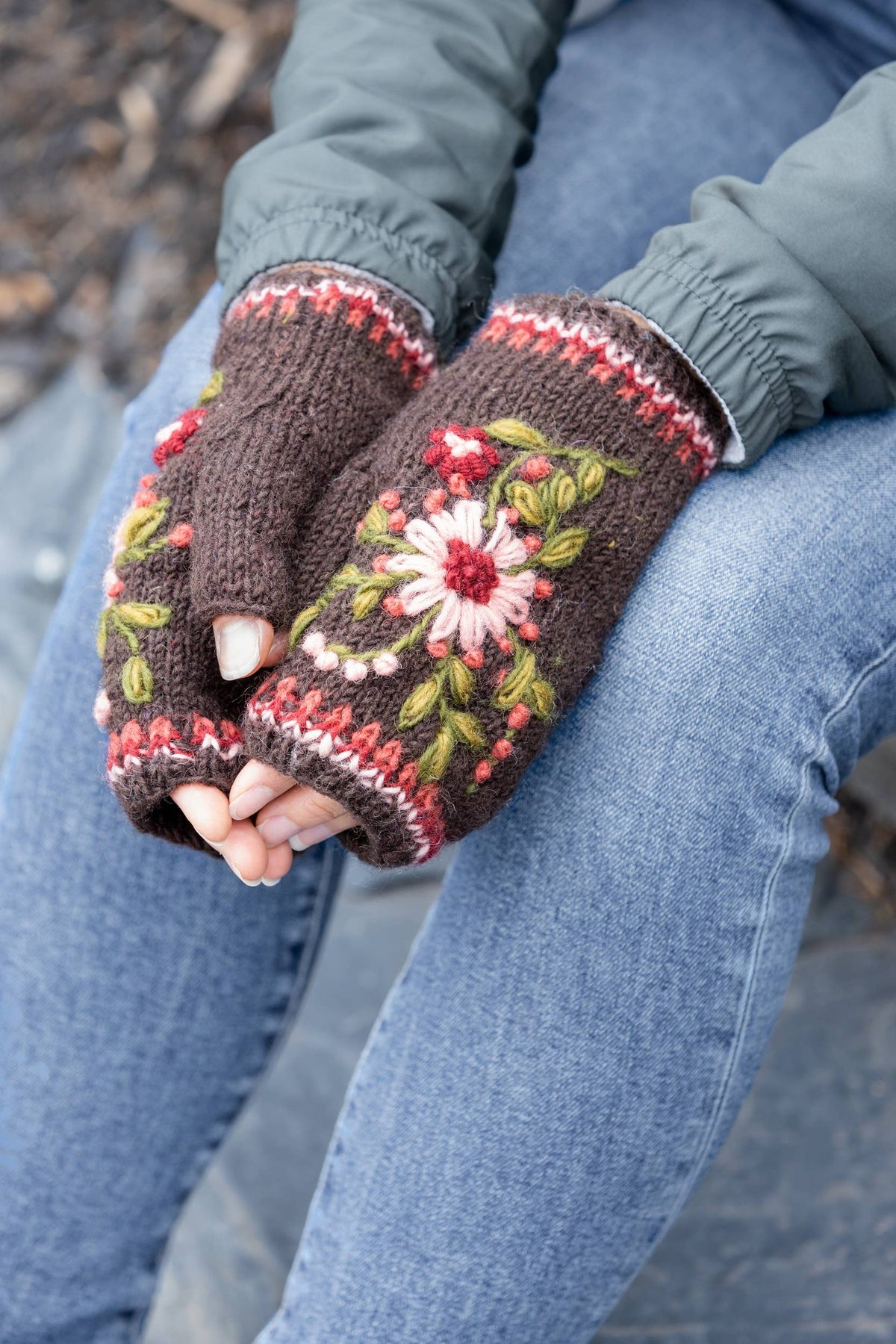 Brown floral-embroidered knit wool handwarmers with red striped cuffs on hands