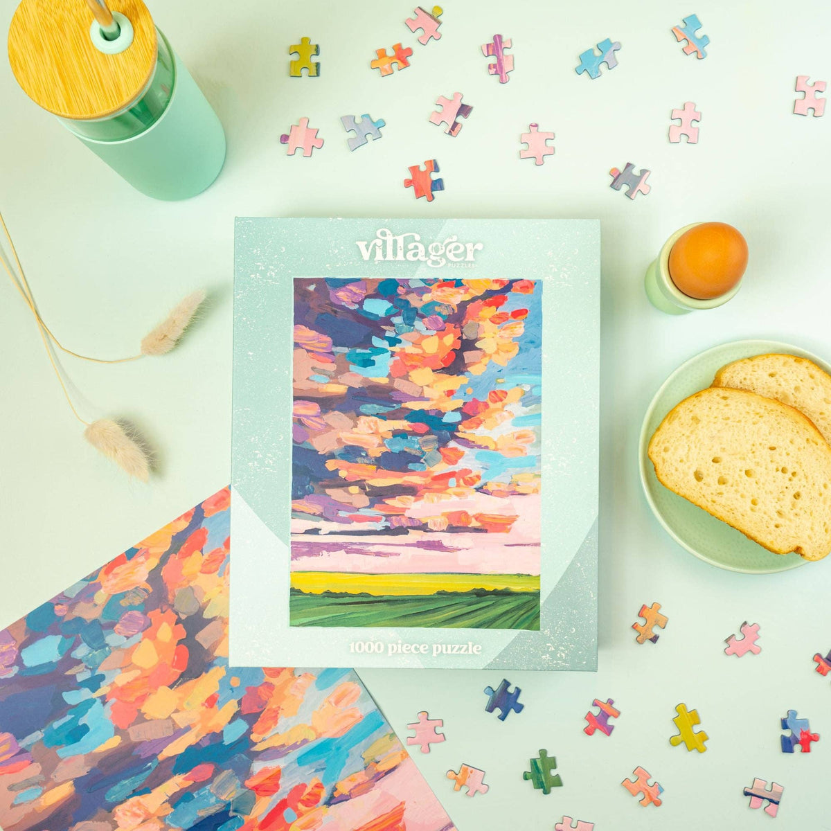 1000-piece puzzle with colorful prairie sky landscape art, shown with loose jigsaw pieces
