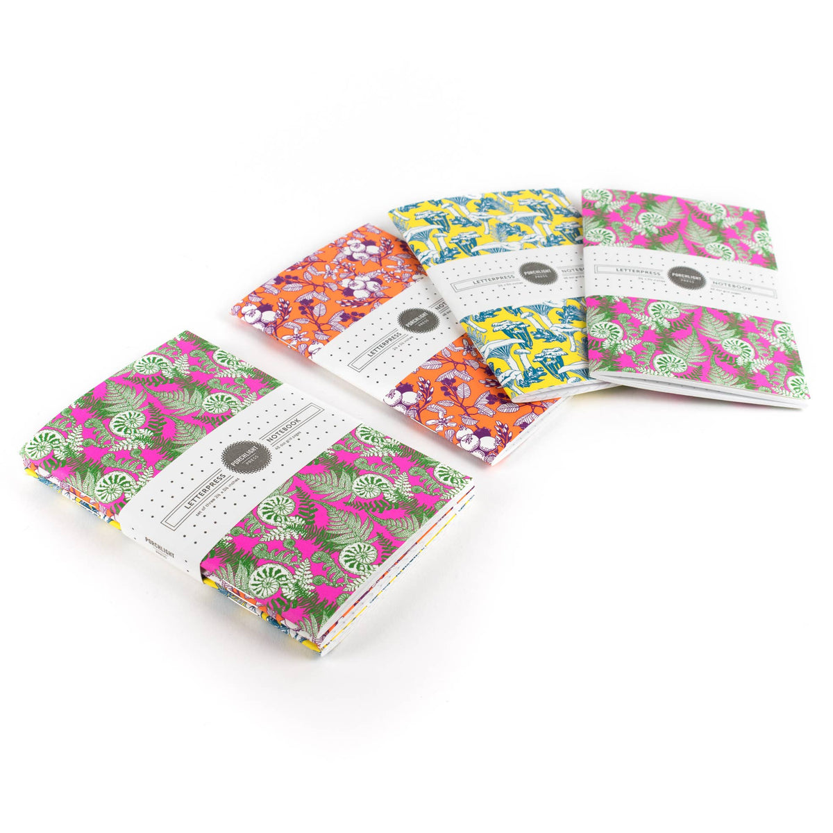 Three pocket notebooks with patterned covers in blue, orange, and pink tones